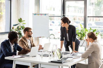 multiethnic businesspeople sitting at tables during conference in office