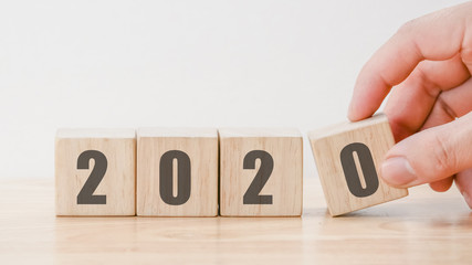 2020  New year countdown design concept , hand holding wood blocks cubes on wooden table  background