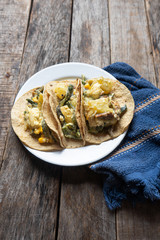 Mexican tacos of poblano rajas with potatoes and sour cream on wooden background