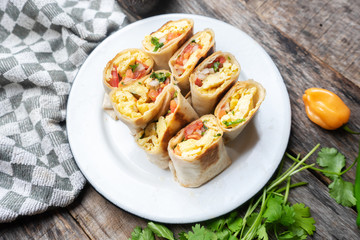 Mexican egg burritos with fresh sauce on wooden background