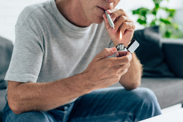 cropped view of man in t-shirt lighting up blunt with medical cannabis