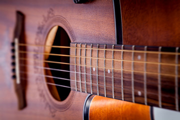 Strings on the fretboard of an acoustic guitar.