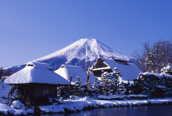 富士山と忍野八海の茅葺屋根の雪景色