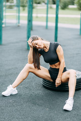 Training and posing with a tire. Beautiful athletic girl on the Playground.