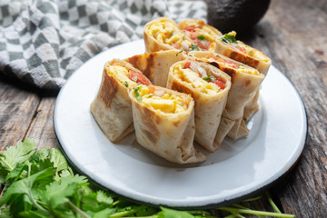 Mexican egg burritos with fresh sauce on wooden background