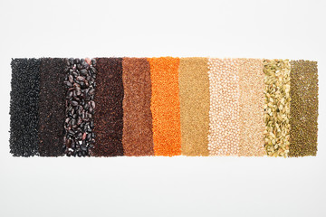 top view of assorted black beans, rice, quinoa, buckwheat, chickpea, red lentil and pumpkin seeds isolated on white