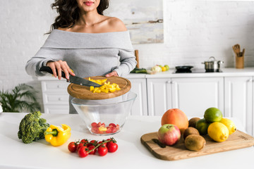 cropped view of happy girl holding knife and cutting board