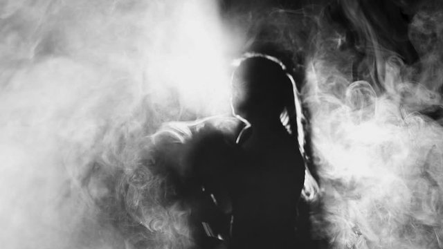 Woman boxer fight does blows in smoke, concept of boxing, self-defense team, slow motion. Black and white