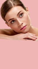 Attractive woman with natural makeup dreaming on pink background. Aspect ratio and vertical...