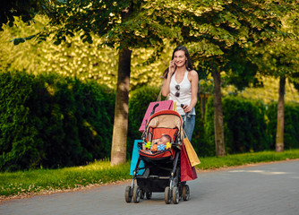 Young woman with baby stroller enjoying talk on phone