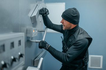 Robbers in black uniform trying to open vault lock