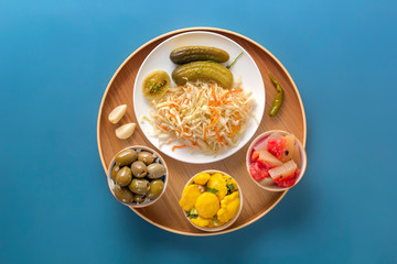 Fermented products cabbage, peppers, pickles, tomatoes, mushrooms, zucchini, garlic on a blue table. Top view. Copy space
