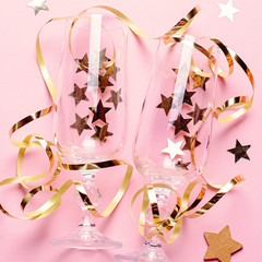 Christmas card with champagne glasses with confetti and streamers in pink and gold colors