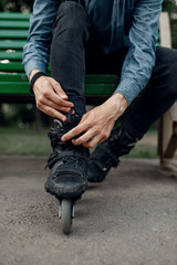 Roller skating, male skater puts on skates in park