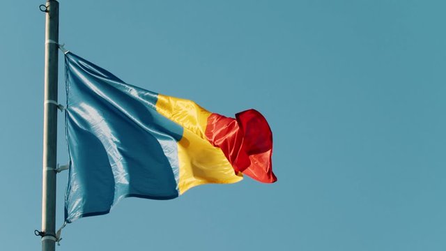 Flag of Romania blowing in the wind on the background of clear blue sky