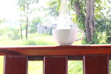 Close up white coffee cup on wood table and view of morning