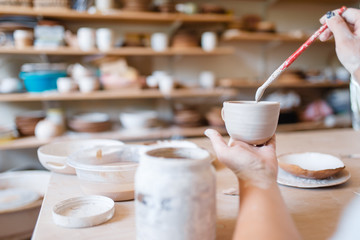 Female potter paints a pot, pottery workshop