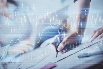 A woman hands writing information about stock market in notepad. Forex chart holograms in front. Concept of research. Double exposure