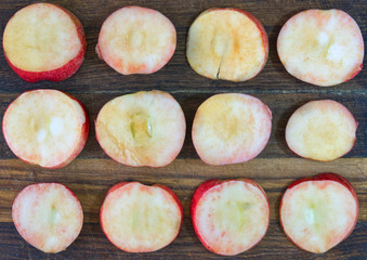 Sliced apples. Round slices of red apples lie on an old wooden board prepared for harvesting by drying.
