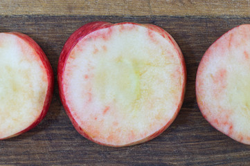 Sliced apples. RouSliced apples. Round slices of red apples lie on an old wooden board prepared for harvesting by dnd slices of red apples lie on an old wooden board prepared for harvesting by drying.