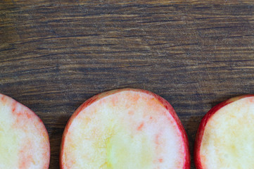 Sliced apples. Round slices of red apples lie on an old wooden board prepared for harvesting by drying.