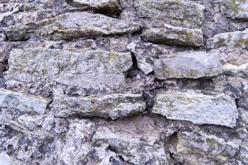 Masonry. The ancient wall is folded and large rough rough stones bonded with clay-lime mortar. The texture of wild stone.