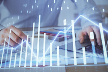 Forex graph with businessman working on computer in office on background. Concept of hardworking. Double exposure.