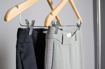 black and grey trousers on hangers