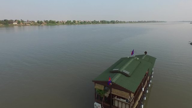 Aerial shot flying over an old traditional wooden Mekong River Cruise boat in the colonial style. The Mekong is the longest river in south-east Asia, Here we see the vastness and width of the river
