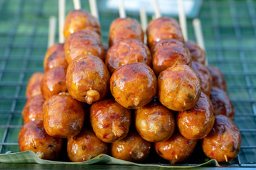 Grilled Thai sausage at street food market in Thailand, closeup. Traditional Thai sausage with pork and rice, delicious street food