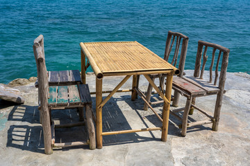 Bamboo table and wooden chairs in empty cafe next to sea water in tropical beach . Island Koh Phangan, Thailand