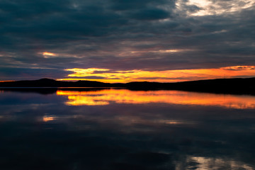 Water reflections at midnight sun at serene lake in finlandd