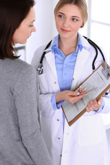 Young woman doctor and patient at medical examination at hospital office. Blue color blouse of therapist looks good. Medicine and healthcare concept