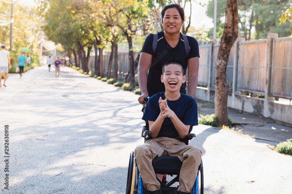 Wall mural Disabled child on wheelchair is playing in the outdoor park like other people, He has a young aunt to take care of closely, Life in the education age of special children, Happy disability kid concept.