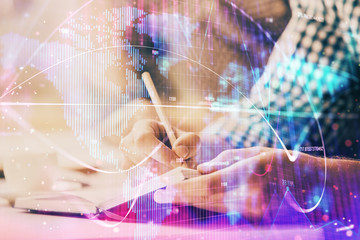 Double exposure of Man writing in notepad with business icons on background.