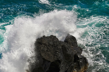 Huge atlantic ocean wave splashing onto a volcanic black rock formation at the Azores on a sunny...