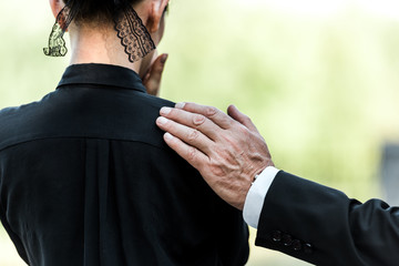 cropped view of elderly man touching woman on funeral - obrazy, fototapety, plakaty