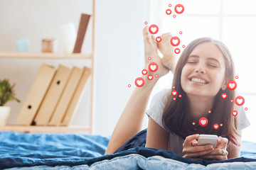 A beautiful young woman blogger, vlogger or influencer is receiving emoji and emoticon reactions in her mobile smart phone device while making a post, sharing or video logging on social media