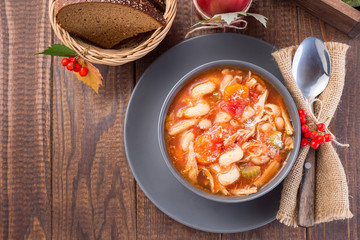 Soup with turkey, pasta, carrot, celery, tomato and cannellini beans, garnished with parmesan cheese, on table with autumn decoration, US Thanksgiving harvest feast, horizontal, top view, copy space