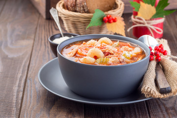 Soup with turkey, pasta, carrot, celery, tomato and cannellini beans, garnished with parmesan cheese, on the table with autumn decoration, US Thanksgiving harvest feast, horizontal, copy space