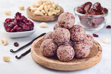 Healthy homemade energy balls with cranberries, cashew nuts, dates and vanilla on a wooden plate, horizontal