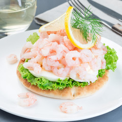 Traditional savory swedish sandwich with soft white bread vetekaka, lettuce, eggs, mayonnaise, shrimps, dill and lemon, square