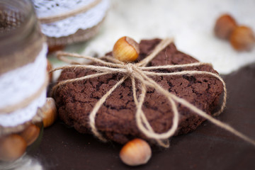 Hazelnuts in the peel and oatmeal cookies on brown table.   Close up image