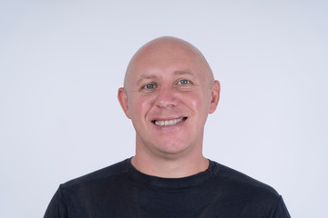 Portrait of middle-aged caucasian bald man looking straight at camera, close up
