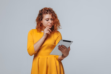 Naklejka premium Red-haired girl looks at the tablet