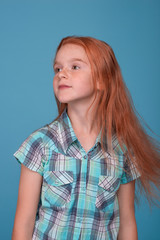 Shot of a little funny redhead  girl  against  blue background