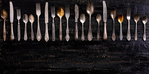 Vintage cutlery - spoons, forks and knives on an old wooden background.