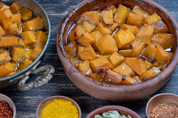 Baked yellow pumpkin with honey, anise, olive oil and spices on a plate on the wooden table. Vegetarian food. Closeup