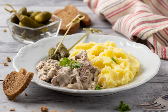 Beef Stroganoff, traditional Russian dish of goulash with beef in creamy sauce, mashed potatoes and pickles. Serve with rustic bread