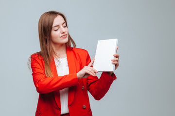 girl in a red jacket holds a presentation of the book on a gray background